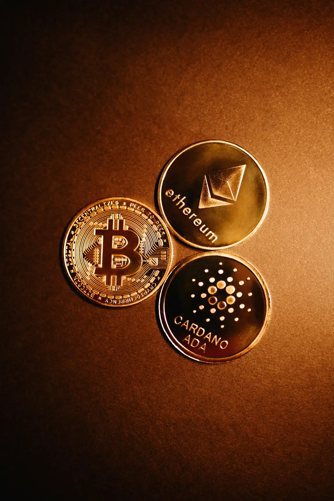 Bitcoin, Ethereum og Cardano på brun bakgrunn